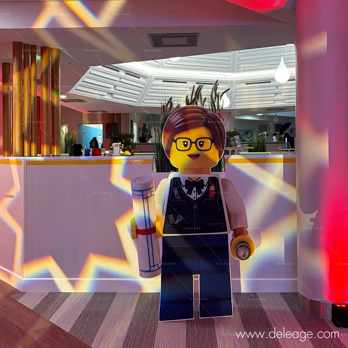 4-decore-evenementiel-sur-mesure-lego-architecte Silhouette LEGO architecte devant une zone de bar éclairée.