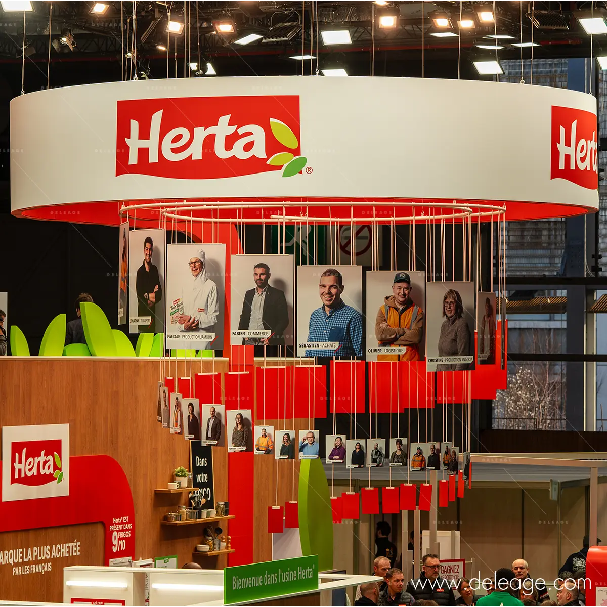 signaletique-stand-herta-sia-2026-bandeau-suspendu-galerie-portraits Stand Herta SIA 2026 – bandeau circulaire suspendu imprimé en grand format et galerie portraits sur structure filaire, réalisation Deleage